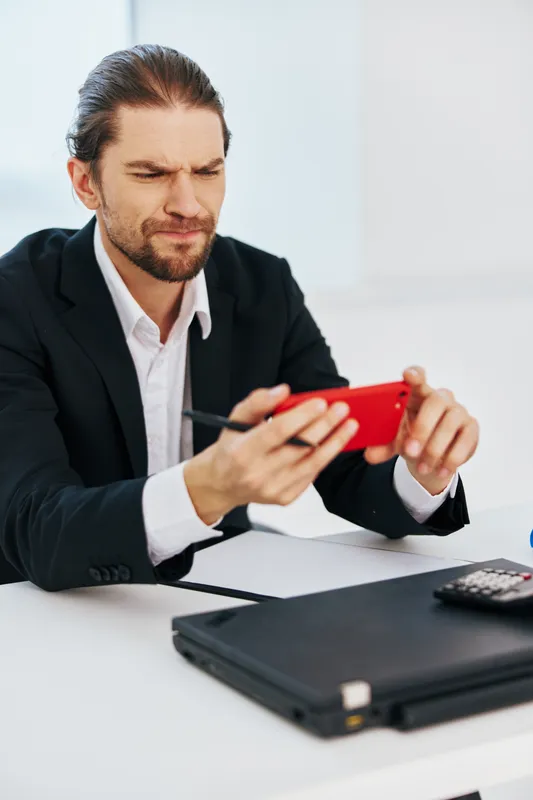 Менеджер работает с документами в офисе, держа в руке телефон