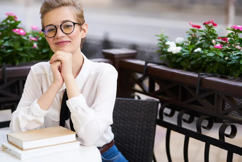 Женщина в рубашке и галстуке за столом с книгой