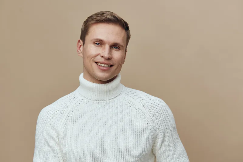 Smiling man in white knitted sweater beige background mental health gadgets digital detox concept casual lifestyle portrait
