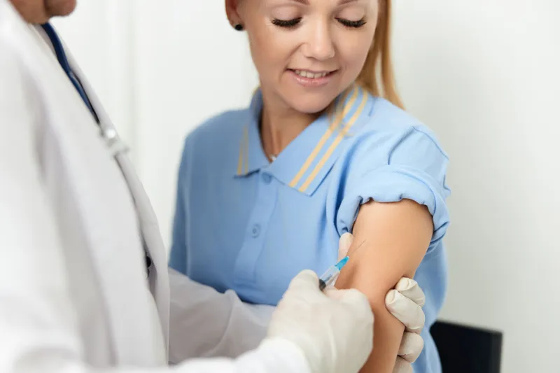 Врач-мужчина делает пациенту укол в руку, вакцинация