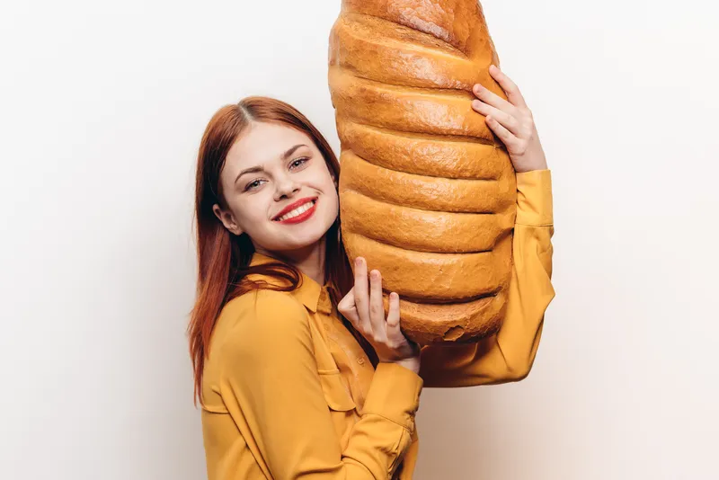 Женщина с батоном в руках на светлом фоне, эмоции, модель, веселье