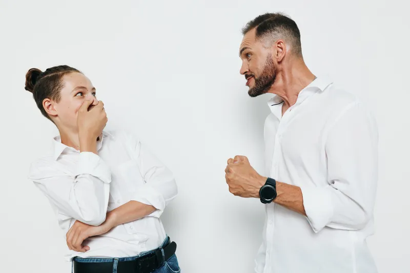Professional man in a smart shirt engages on an isolated colored backdrop, showing strong emotion and focus as he discusses a business topic with a colleague.