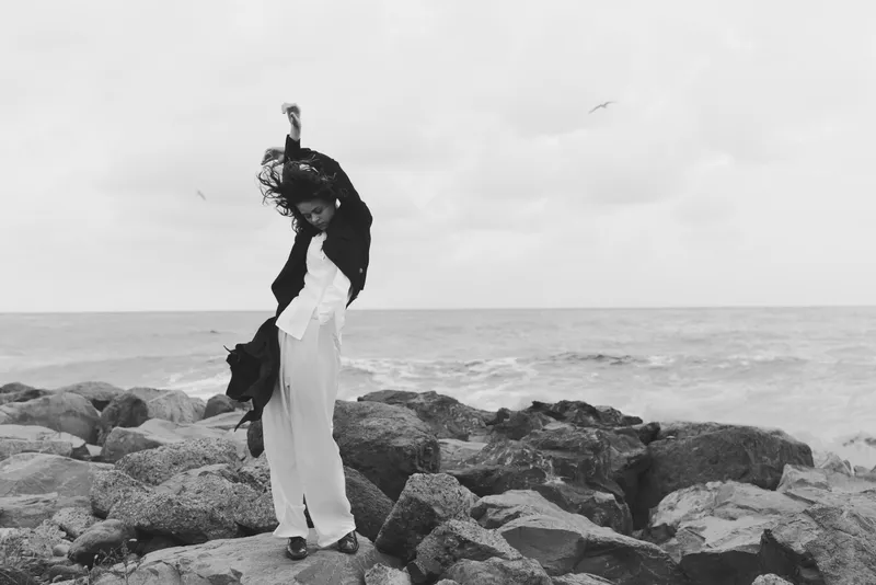 Sea, rocks, woman, dress, freedom, wind, monochrome, ocean, movement, coastline photo of a figure raising arms on a rocky shore in black and white