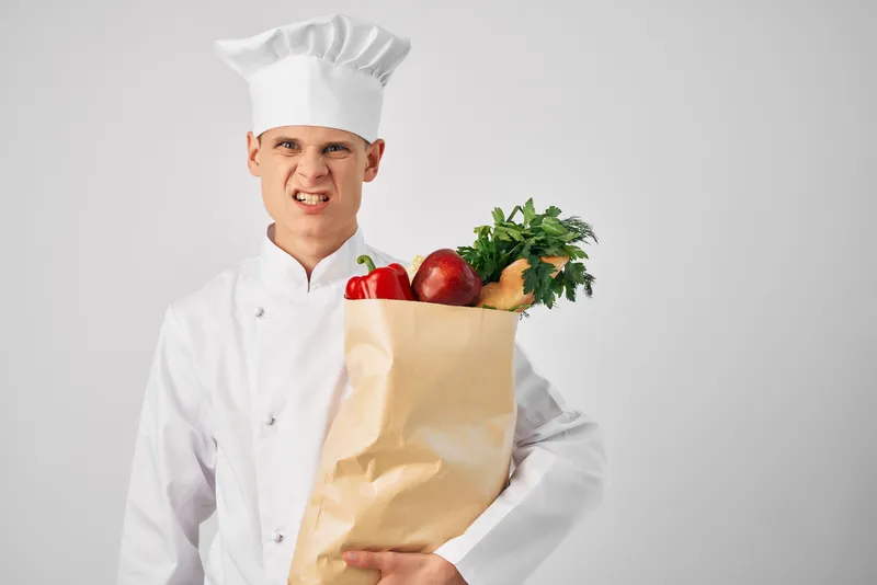 Мужчина в униформе повара с упаковкой продуктов для доставки из ресторанной службы