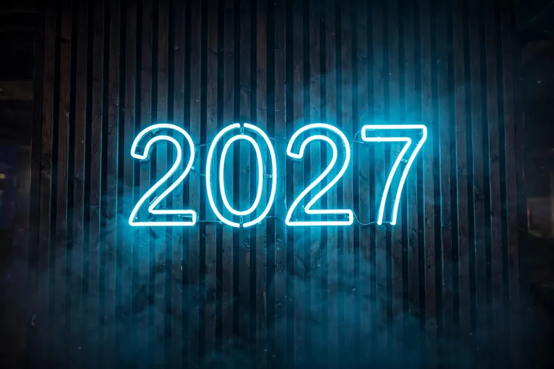 Неоновая надпись 2027 на тёмной стене в синем свете