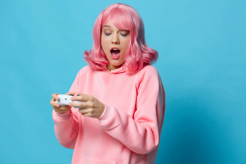 Молодая женщина играет в игры с джойстиком, веселится, изолированный фон
