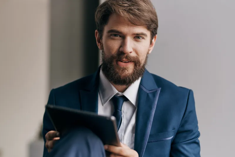 Весёлый бизнесмен с планшетом в руках общается по работе