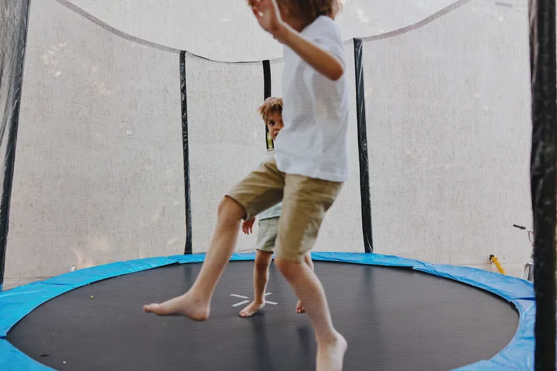 Energetic children having fun on a trampoline, showcasing joy and playfulness in a vibrant outdoor setting, perfect for family-focused content.