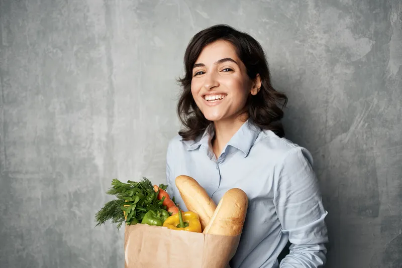 Брюнетка с продуктовым пакетом в супермаркете, овощи, диетическое питание