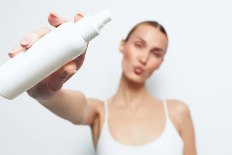 Woman skincare lotion moisturizing body beauty spa hygiene, hand holds lotion dispenser, woman applies moisturizing body cream, blurred female in white top, bright clean bathroom, soft skin care