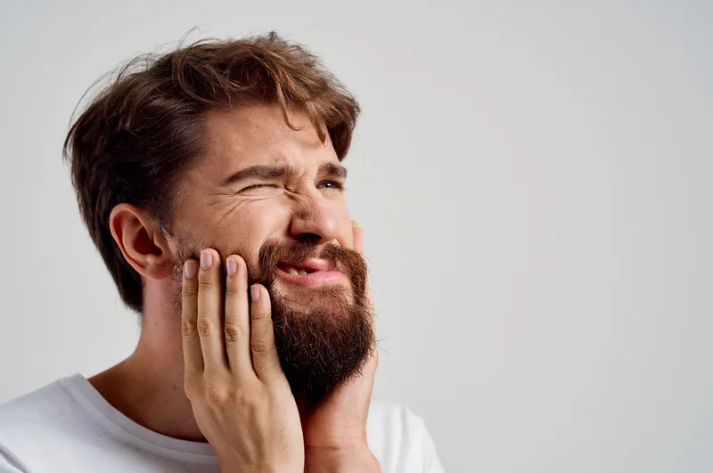 Мужчина испытывает зубную боль, что иллюстрирует проблемы со здоровьем и медицину на изолированном фоне