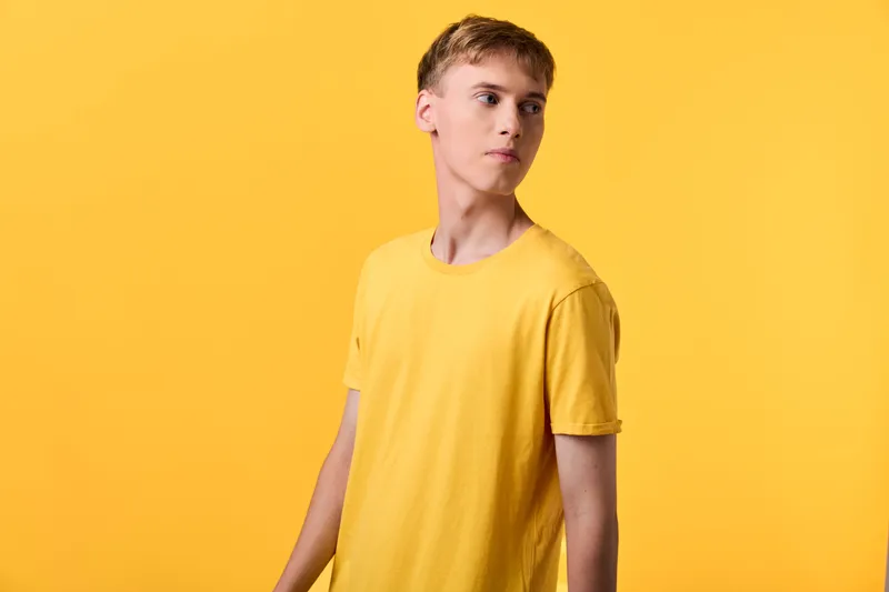 Young man in a yellow tshirt standing against a matching yellow backdrop, casual fashion and color harmony, studio shot emphasizing bright monochrome palette and relaxed mood for lifestyle and design