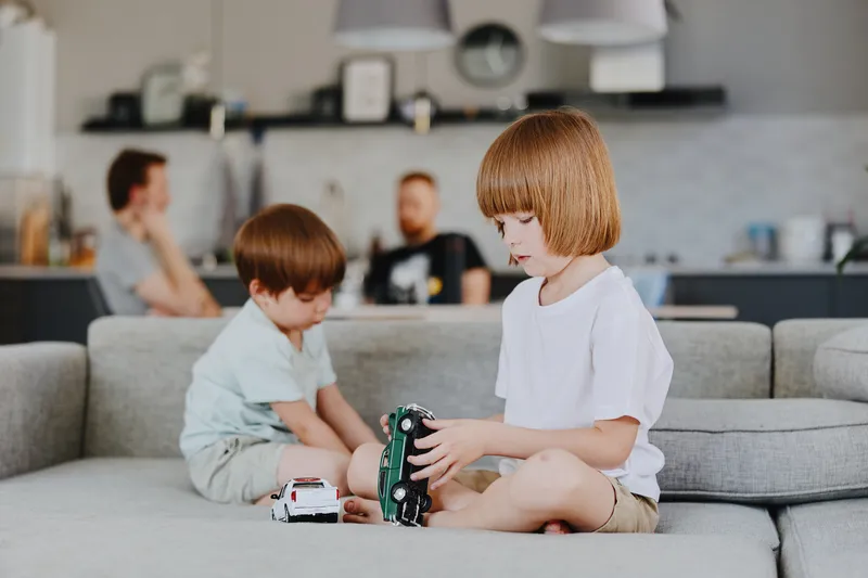 Two boys playing with toy cars, showcasing creativity and joy in a cozy living room setting, with an inviting ambiance and soft colors enhancing the playful atmosphere.