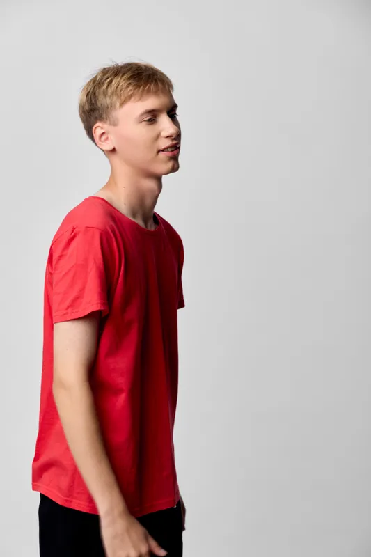 Man, profile, red shirt, casual, studio, side view, youth, relaxed, pose, clothing, fashion, lifestyle, calm, simple, clean, minimal, everyday, contemporary, male, t shirt, standing, neutral