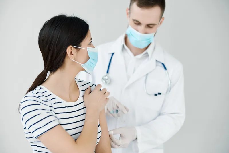 Мужчина делает инъекцию в плечо пациенту — вакцинация, защита здоровья