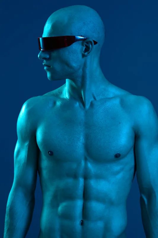 Blue-toned man showcasing a muscular physique, wearing stylish sunglasses. The vibrant background creates a striking visual contrast, enhancing the image's appeal.