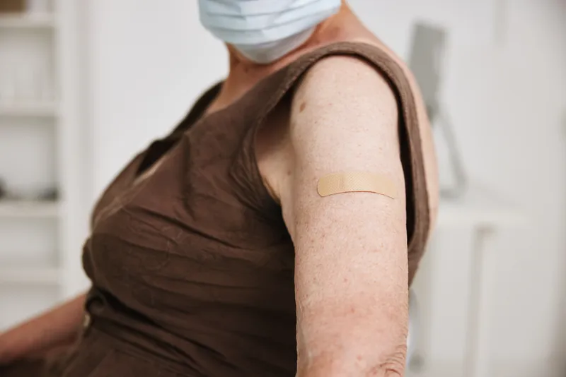 Пациент в клинике держит вакцинный паспорт COVID-19, крупный план