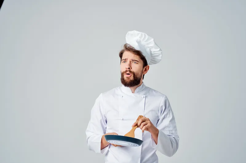 Профессиональный повар жарит еду на сковороде, работая на кухне
