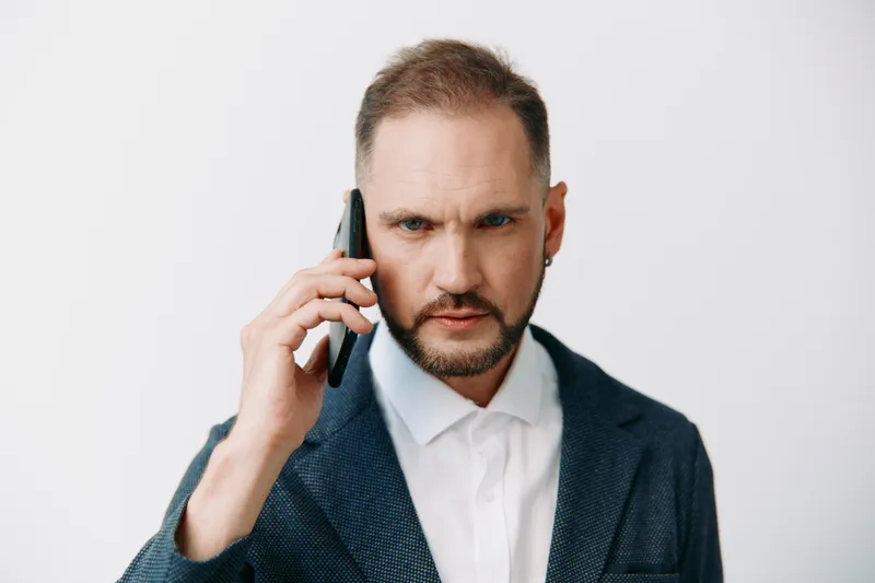A focused business professional on a colored isolation background, speaking on a phone with intense emotion, portraying drive, precision, and clear communication in a corporate setting.