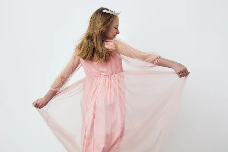 Young girl in a pink dress elegantly twirling, showcasing flowing fabric and joyful expression against a light background Perfect for children s fashion and ethereal themes