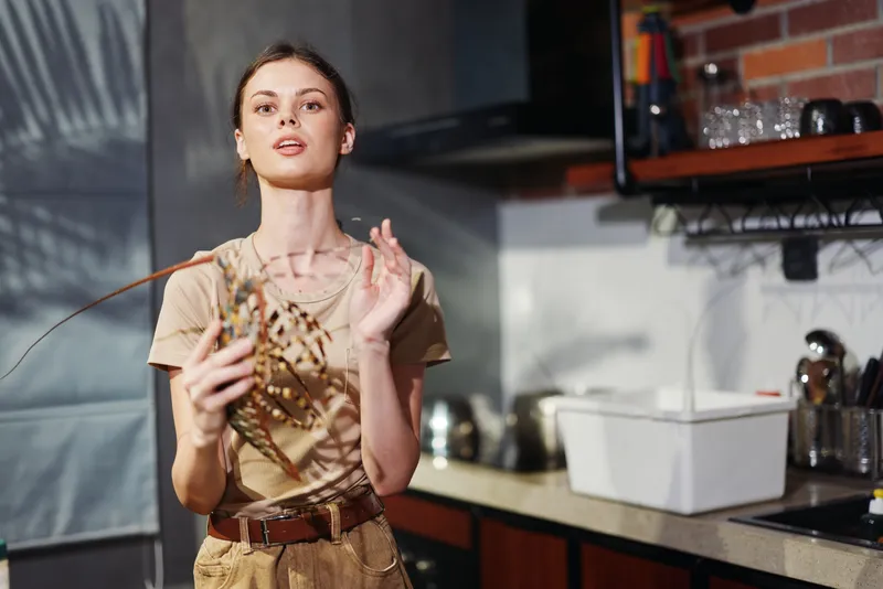 Женщина держит кусок мяса на кухне и смотрит в камеру перед приготовлением еды