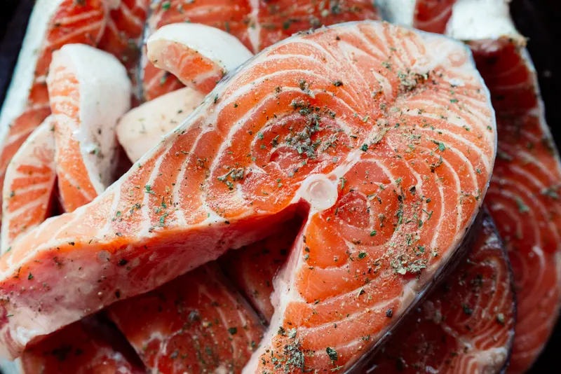 Маринованная красная рыба на тарелке, приготовление морепродуктов, деликатес