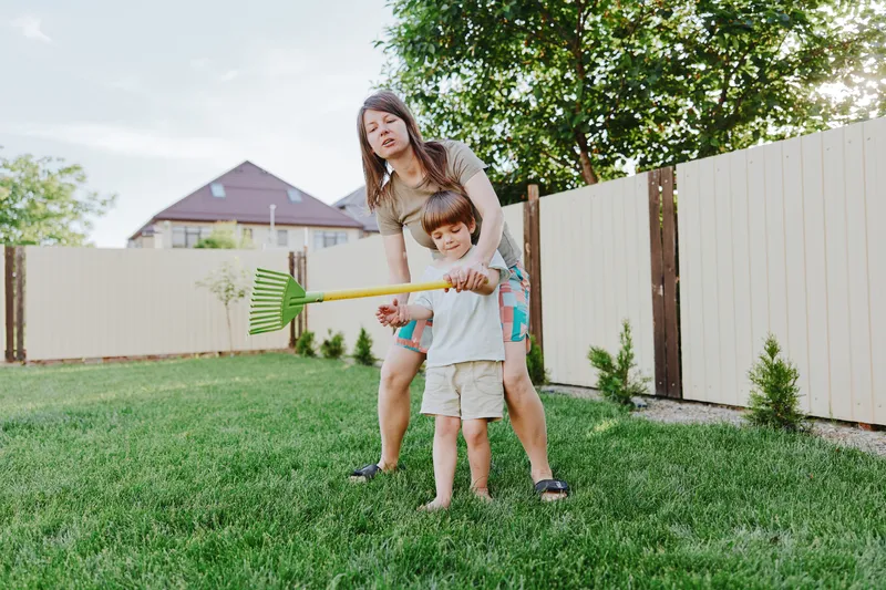 Active woman gardening with her son, enjoying a sunny day outdoors. A fun and playful atmosphere enhances the joy of family time in the garden.