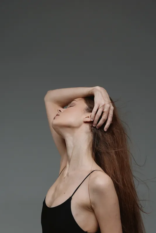 graceful woman posing with hand in hair, long red hair, black top, elegant and calm mood