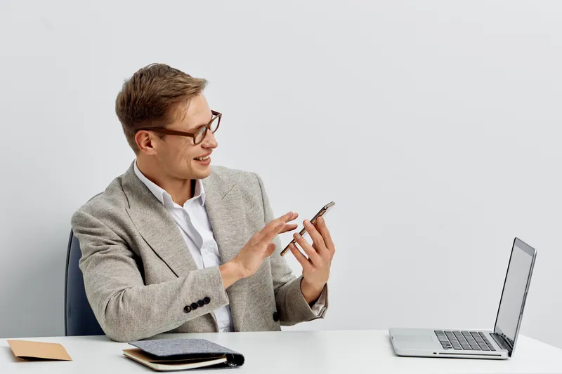 smiling caucasian man working digital nomad using smartphone laptop indoor communication technology concept