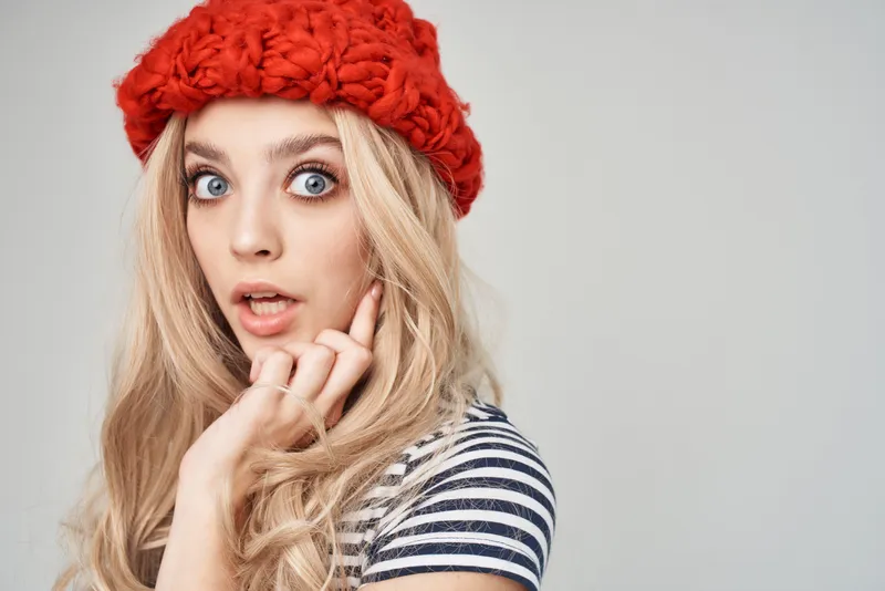 Блондинка делает жесты руками, наносит макияж и позирует в студии