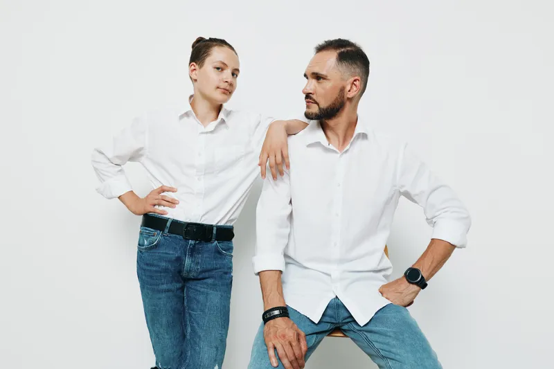 A confident business professional man stands with a relaxed pose against a solid colored background, exuding focus, readiness, and strong demeanor to invite collaboration.