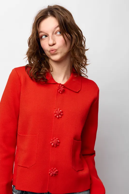 Young woman in red sweater looks sideways with playful expression. Casual style, studio portrait on white background. Concept of youth, fashion, and personality.