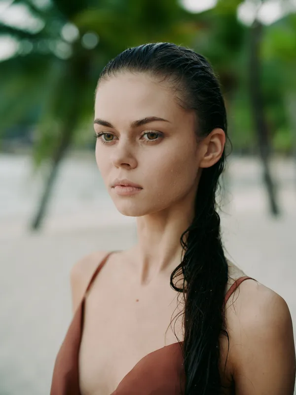 serious young woman with wet dark hair outdoors, natural makeup, blurred green background, summer vibe, contemplative expression