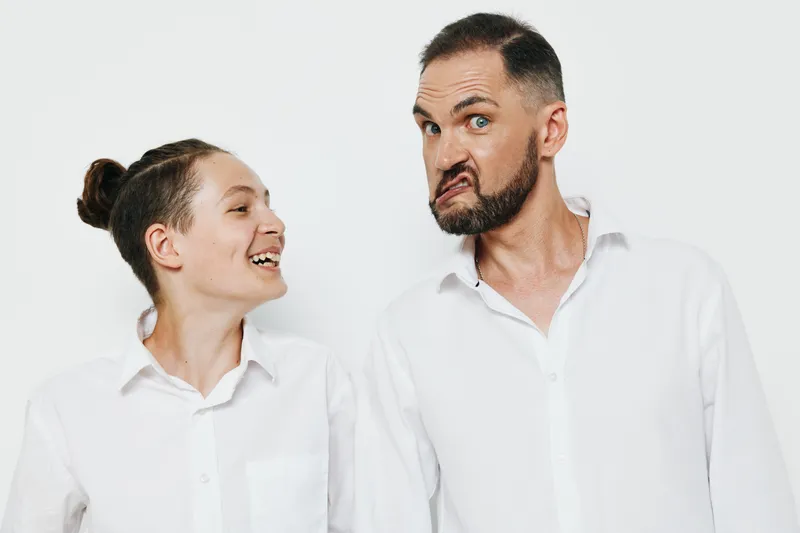Professional man in a business setting stands beside a colleague, showing confident emotion. Isolated white background highlights posture, gaze, and leadership in a modern work scene.