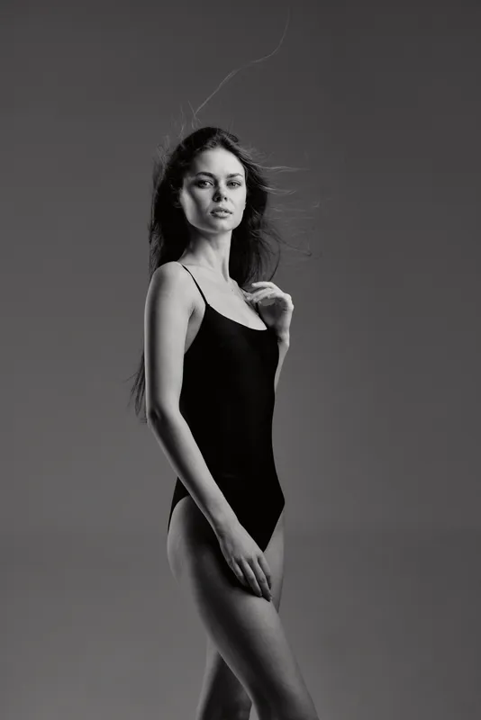 black and white portrait of a slender woman in a black bodysuit with serious expression