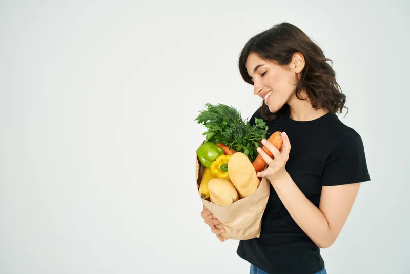 Симпатичная брюнетка в черной футболке с пакетом продуктов из супермаркета