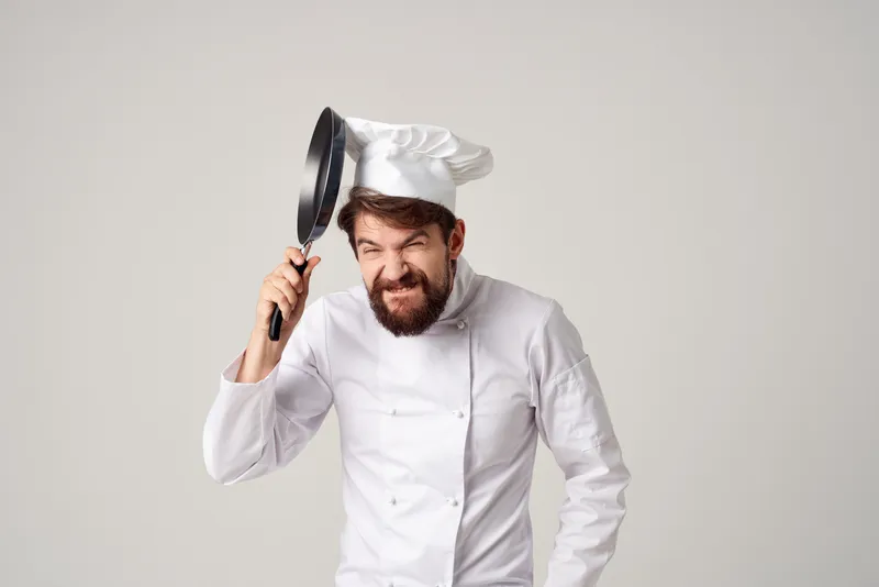 Мужчина в поварской форме с кастрюлей готовит на кухне на изолированном фоне