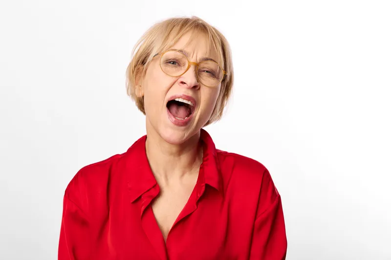 Woman, senior, surprised, shocked, mouth open, red blouse, white background, studio portrait, expressive face, gasp reaction, close up headshot, emotion, disbelief