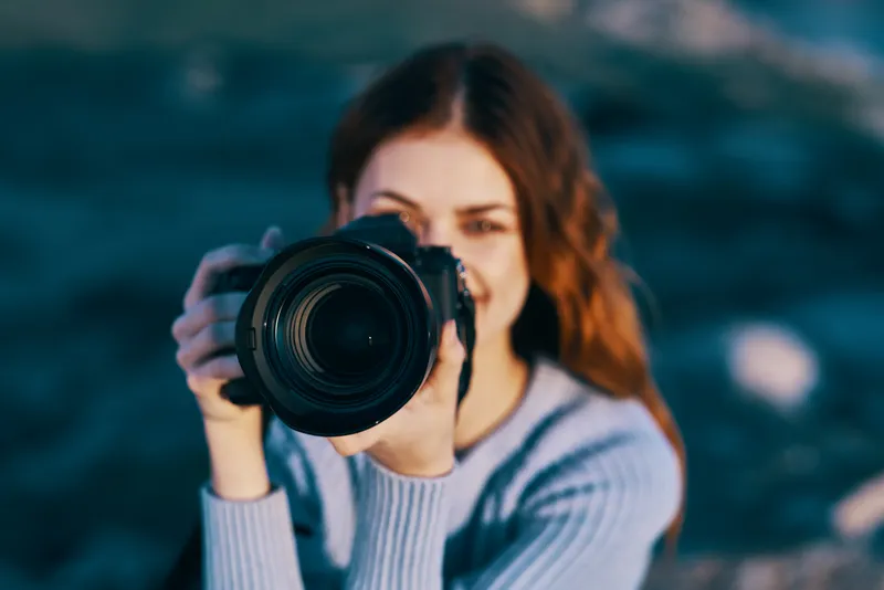 Крупный план симпатичной женщины-фотографа на природе среди скалистых гор, профессиональный вид