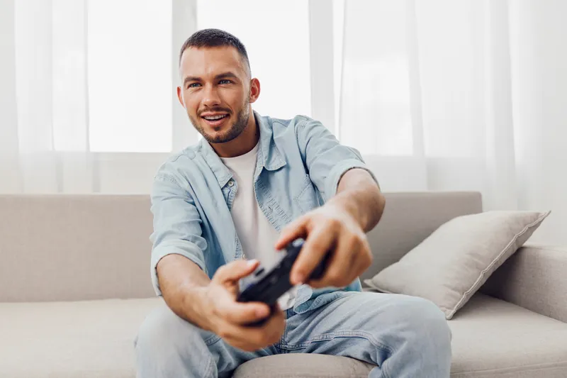 Engaged man playing video games at home, showcasing a moment of relaxation and connection amidst digital distraction and the challenges of modern life.