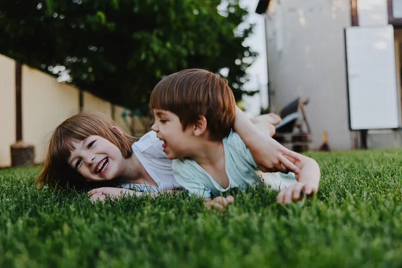 Happy children playing outside on fresh green grass, enjoying their summer day in a joyful atmosphere with laughter and friendship. ###