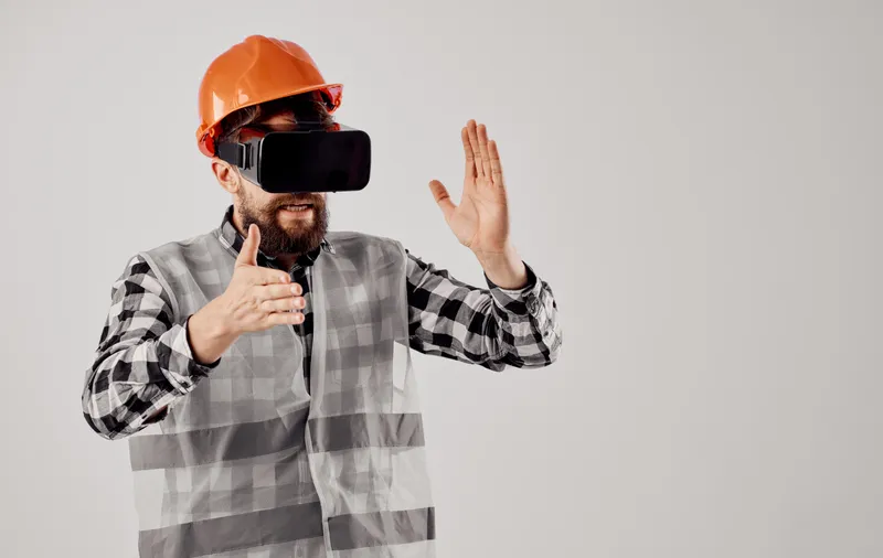Инженер-строитель в оранжевой каске и 3D-очках на светлом фоне