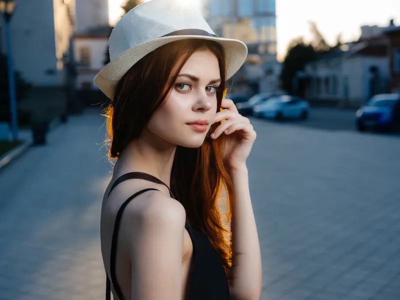 Привлекательная женщина в шляпе позирует на улице летом