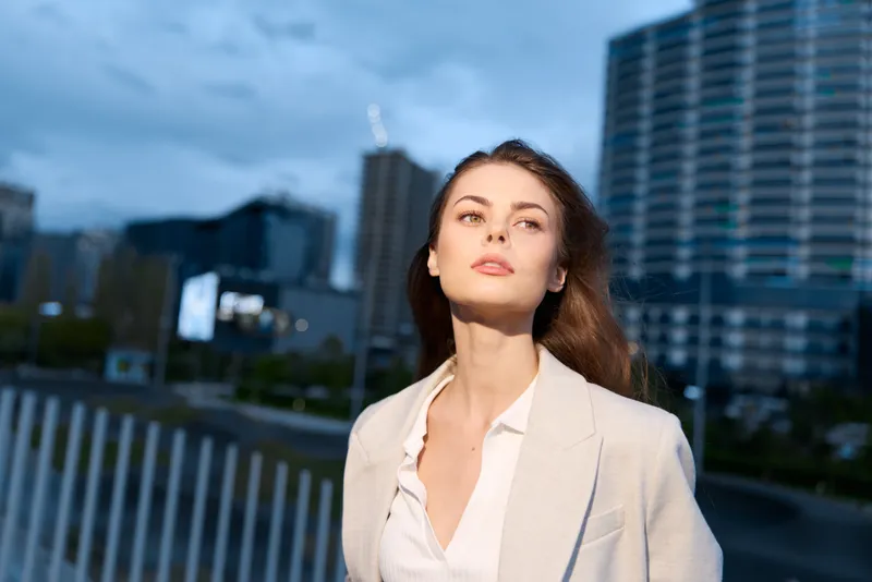 Confident woman in business attire against a modern city backdrop, showcasing elegance and professionalism, perfect for corporate themes.