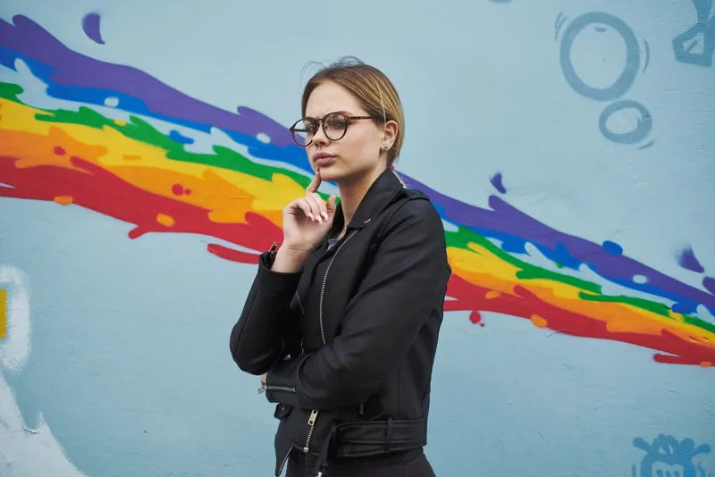 Женщины стоят рядом с граффити на стене в виде радуги на улице