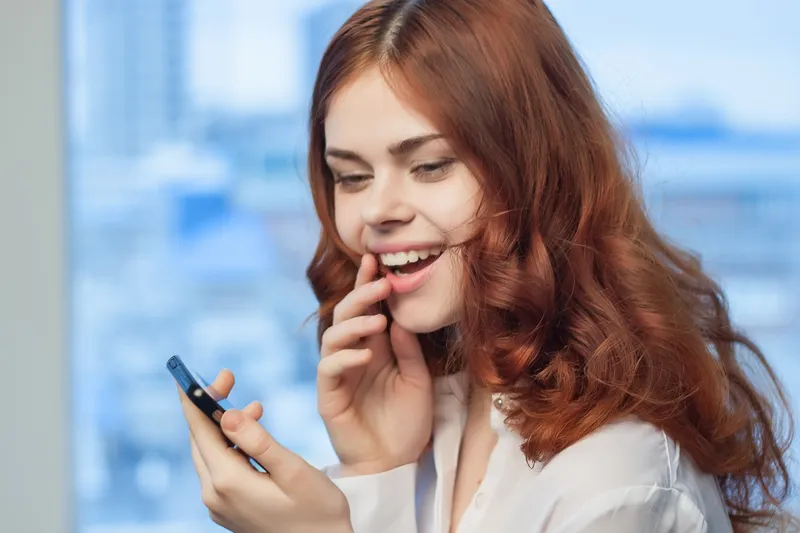 Рыжеволосая женщина с телефоном в руках общается с официальным лицом
