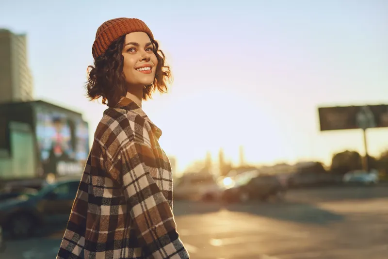 woman smile golden urban candid beanie plaid lifestyle portrait sunlight young woman walking at sunset with authenticity and candid lifestyle, golden hour glow and mindful living, emotional