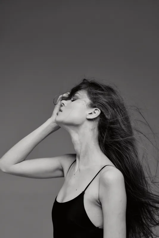Black and white profile of a woman with long hair posing thoughtfully with closed eyes and delicate expression