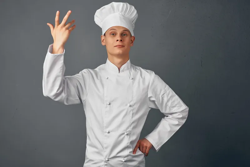 Шеф-повар жестикулирует руками на профессиональной кухне, создавая атмосферу гурманства
