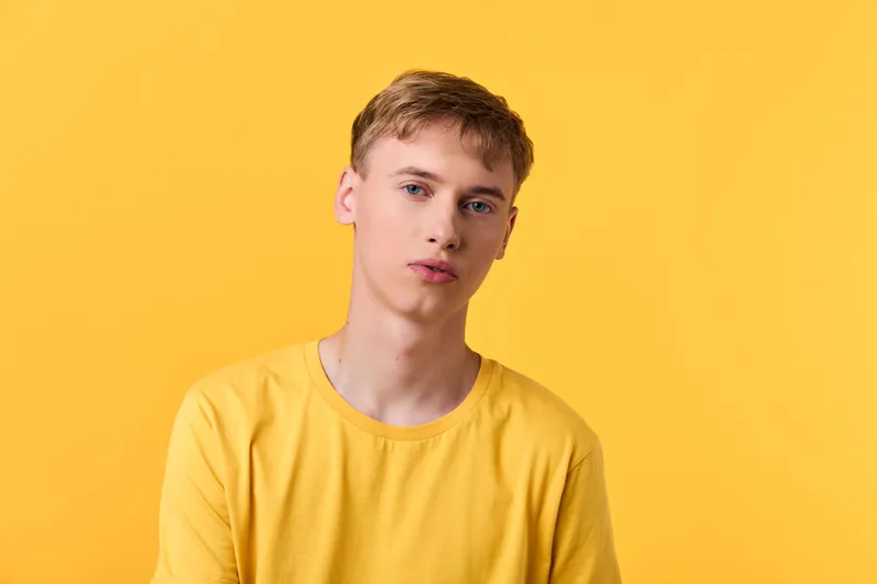 Yellow shirt worn by a young man against a vivid yellow backdrop, creating a bold, minimal studio shot for fashion branding, lifestyle color stories, and modern visual marketing